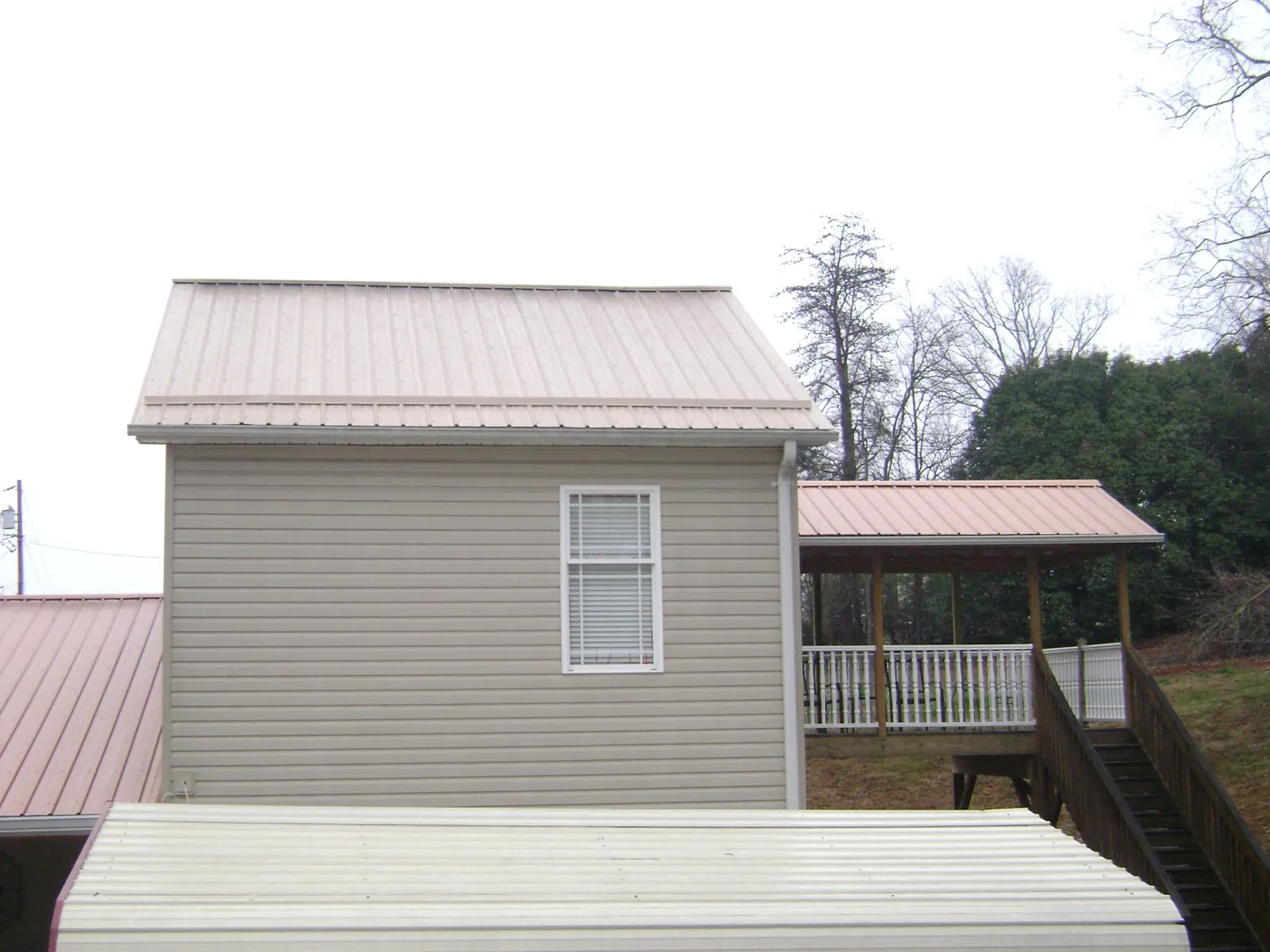 Tan metal roofs on a two story addition and attached porch, from a Roof Replacement job in San Ysidro
